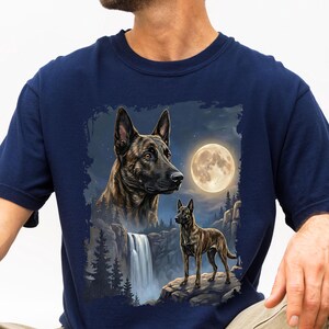 May include: Navy blue t-shirt featuring a detailed illustration of two dogs, a waterfall, and a full moon. The design showcases a larger dog's head and a smaller dog standing on a rock, with a night sky backdrop.