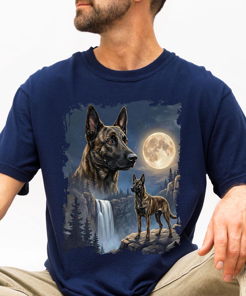 May include: Navy blue t-shirt featuring a detailed illustration of two dogs, a waterfall, and a full moon. The design showcases a larger dog's head and a smaller dog standing on a rock, with a night sky backdrop.