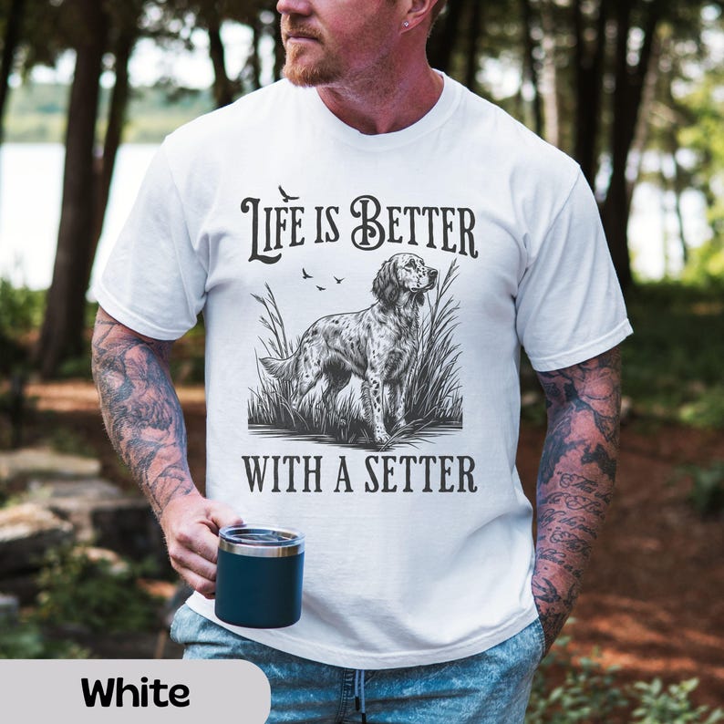 May include: White t-shirt with the text "Life is Better With A Setter" above a black and white illustration of a setter dog in tall grass. The shirt is a crew neck style.