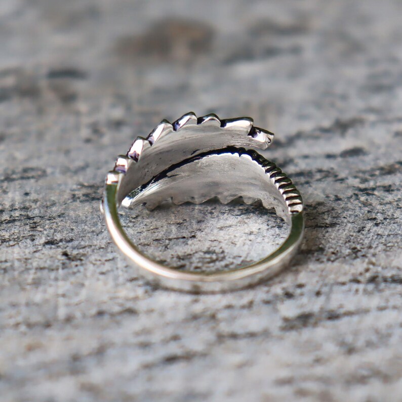 Puede incluir: Un anillo plateado con dise&ntilde;o de hoja. El anillo presenta un dise&ntilde;o de hoja detallado y texturizado que envuelve el dedo. La banda tiene un acabado liso y pulido, y la hoja tiene intrincadas vetas y bordes.