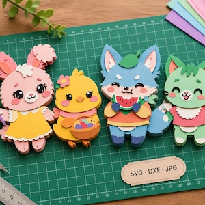 May include: Four layered paper craft figures including a pink rabbit with a yellow star wand, a yellow chick holding a basket, a blue fox eating a watermelon slice, and a green cat holding an ice cream cone. A label reads SVG, DXF, JPG.