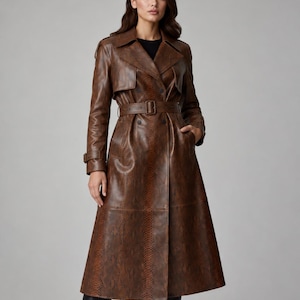 Peut inclure: Un long trench-coat croisé avec une finition texturée en peau de serpent marron. Le manteau présente un large col, des revers, des épaulettes et une ceinture assortie avec une boucle à la taille. Il possède des manches longues avec des poignets bouclés.
