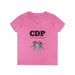 Puede incluir: Una camiseta rosa con cuello en V con el texto negro "CDP" y "Carolina Dance Productions" debajo. Un gráfico de bailarines en movimiento está debajo del texto. La camiseta está hecha de un material suave.