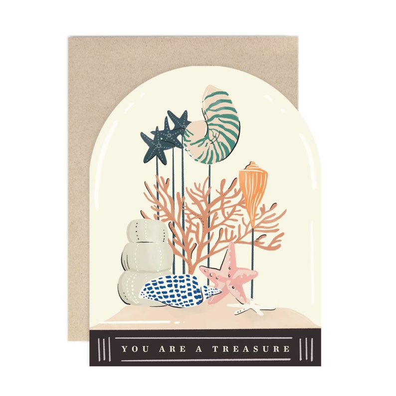 May include: A white card with a dome-shaped illustration of a seashell, coral, starfish, and other sea life. The text "YOU ARE A TREASURE" is printed on the bottom of the card.