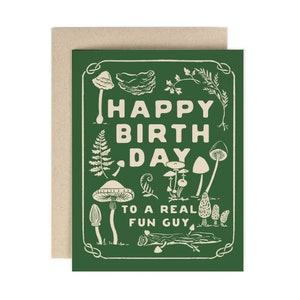 Könnte beinhalten: Grüne Karte mit weißem Rand und weißem Text, der "Happy Birthday to a Real Fun Guy" lautet. Die Karte ist mit Illustrationen von Pilzen, Farnen und anderen Waldelementen verziert.