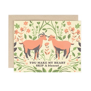 Könnte beinhalten: Eine Grußkarte mit einem Blumenmuster und zwei Ziegen, die sich gegenüberstehen. Der Text auf der Karte lautet "You make my heart skip a bleat."