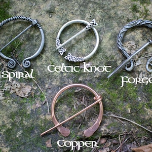 May include: Four different styles of Celtic brooches, each with a unique design. The brooches are made of silver and copper and feature a variety of patterns, including spirals, Celtic knots, and forged designs. The brooches are displayed on a rock background with the names of each style written below.