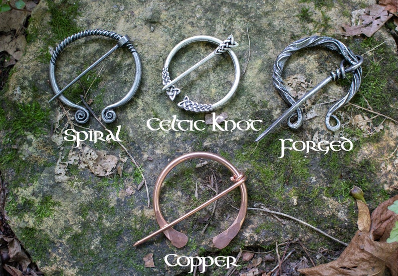 May include: Four different styles of Celtic brooches, each with a unique design. The brooches are made of silver and copper and feature a variety of patterns, including spirals, Celtic knots, and forged designs. The brooches are displayed on a rock background with the names of each style written below.