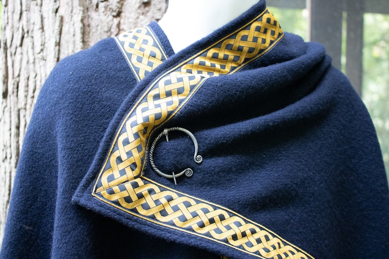 May include: A navy blue shawl with a gold Celtic knot trim and a silver ring brooch.