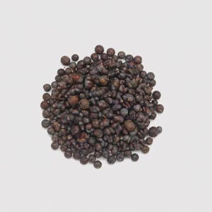 Könnte beinhalten: Ein Haufen dunkelbrauner, runder Objekte, möglicherweise Samen oder kleine Beeren, vor einem weißen Hintergrund. Die Objekte haben eine strukturierte Oberfläche und variieren leicht in Größe und Farbton, was ein natürliches, organisches Aussehen erzeugt.