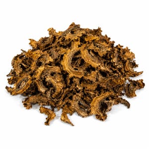 May include: A pile of dried, brown, sliced bitter melon pieces against a white background. The pieces have a ridged, irregular shape and a slightly curled appearance. The color ranges from light to dark brown.
