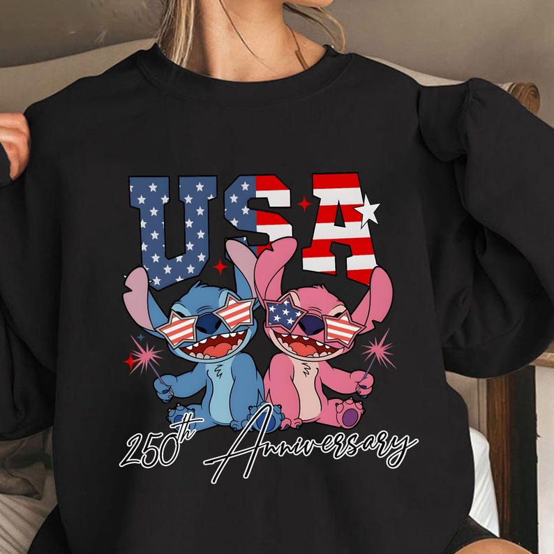 May include: Black sweatshirt with a graphic of two cartoon aliens wearing star-spangled sunglasses and holding sparklers. The word "USA" is in red, white, and blue, with "25th Anniversary" below.