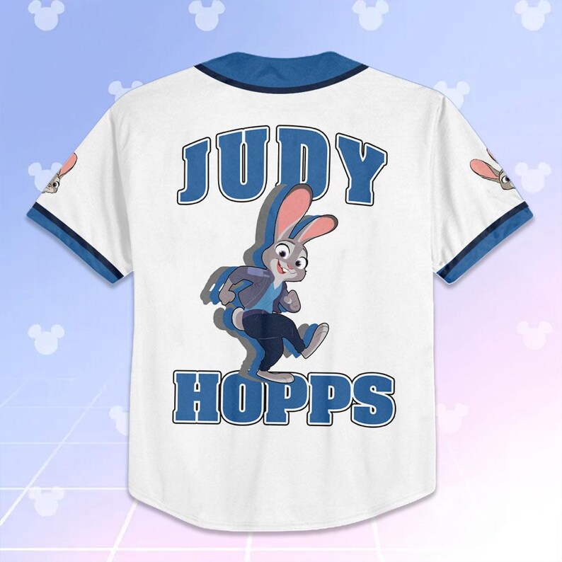 May include: White baseball jersey with blue trim and the name "JUDY HOPPS" in blue block letters. A cartoon image of Judy Hopps, a gray rabbit, is featured on the back. The jersey has short sleeves and a button-up front.