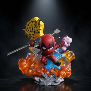 以下が含まれることがあります： 赤と黒のスーツを着たデッドプールのフィギュアが、半透明のオレンジと青の爆発ベースの上を跳躍しています。キャラクターは銀色の刀と小さな白いユニコーンのぬいぐるみを持っており、背後には「WTF!」と書かれた黄色い看板と矢が配置されています。
