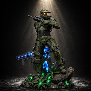 Può includere: Una dettagliata statuetta da collezione di un soldato in armatura verde oliva con visiera dorata, che impugna un fucile nero. La figura poggia su una base rocciosa con luci blu e verdi, con piccole piante verdi e un'arma a energia blu.