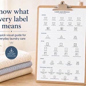 May include: A white paper chart titled Laundry Quick Reference with care label symbols for washing, bleaching, drying, ironing, and professional textile care, held on a wooden clipboard next to a stack of three folded knit towels.