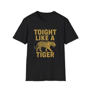 May include: Black t-shirt with the text "TOIGHT LIKE A TIGER" in gold lettering. A gold tiger graphic is centered below the text. The shirt is a classic crew neck style.