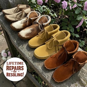 May include: A collection of moccasin-style shoes in various colors and textures, including tan, brown, and yellow suede, and a pair with a white and brown fur pattern. The shoes are arranged on a wooden surface, with laces and stitched details.