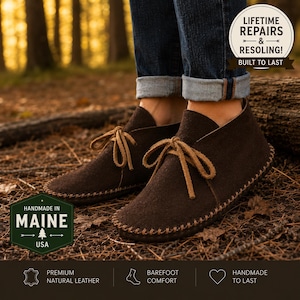 May include: Dark brown suede leather moccasin boots with tan leather laces and visible whipstitch detailing along the sole. The boots are worn with cuffed blue jeans. Text overlays include "LIFETIME REPAIRS & RESOLING!" and "HANDMADE IN MAINE USA".