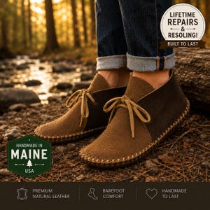 May include: Brown suede ankle boots with a moccasin-style construction, featuring light tan laces and visible whipstitching along the sole. The boots are worn with cuffed blue jeans. Text overlays include 'Handmade in Maine' and 'Lifetime Repairs'.