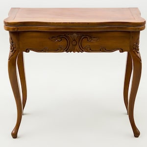May include: A wooden side table with a rectangular top and ornate carved apron. The table has curved legs and decorative carvings. The wood has a warm, medium brown tone. The table is approximately 76 cm long, 51 cm wide, and 71 cm tall.