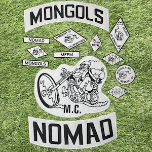 May include: A collection of white and black patches, including a large patch with a motorcycle illustration and the text "M.C.". Other patches include the words "MONGOLS", "NOMAD", and "IN MEMORY OF FALLEN BROTHERS".