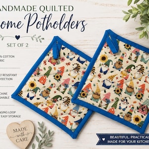 May include: A set of two square quilted potholders featuring a repeating pattern of colorful gnomes, sunflowers, and leaves on a cream background, finished with a solid blue fabric border and a small fabric hanging loop on each corner.