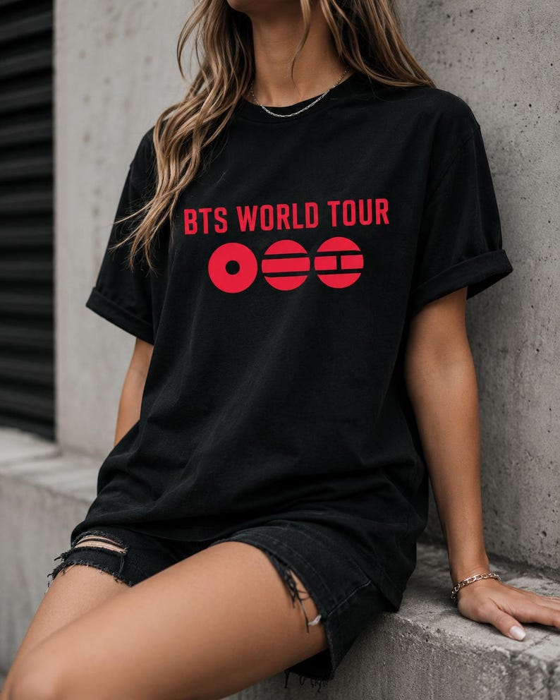 May include: Black t-shirt with the text "BTS WORLD TOUR" in red, along with a red graphic design. The shirt is a casual style, with rolled-up sleeves.