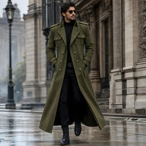 Könnte beinhalten: Ein olivgrüner Trenchcoat mit goldenen Knöpfen und doppelreihigem Design. Der lange Mantel hat einen hohen Kragen, Schulterklappen und Taschen. Die Person trägt einen schwarzen Rollkragenpullover, eine schwarze Hose und schwarze Stiefel. Der Mantel ist ein stilvolles Oberbekleidungsstück.