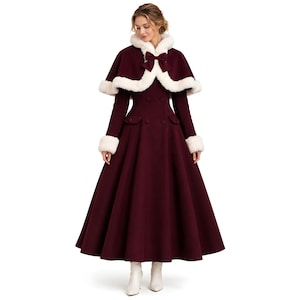 Könnte beinhalten: Burgunderfarbener langer Mantel mit passendem Cape. Das Cape und die Manschetten sind mit weißem Kunstfell besetzt. Der Mantel hat ein doppelreihiges Design und einen weiten Rock. Das Model trägt weiße Stiefel.