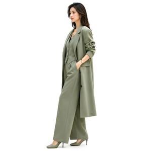 Pu&ograve; includere: Un completo verde oliva a tre pezzi composto da un cappotto lungo, un gilet e pantaloni a gamba larga. Il completo &egrave; realizzato in un tessuto liscio e viene indossato con tacchi abbinati. L'outfit &egrave; una rivisitazione moderna di un classico completo da lavoro.
