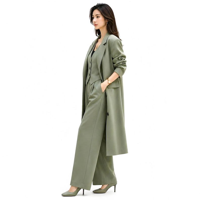 Pu&ograve; includere: Un completo verde oliva a tre pezzi composto da un cappotto lungo, un gilet e pantaloni a gamba larga. Il completo &egrave; realizzato in un tessuto liscio e viene indossato con tacchi abbinati. L'outfit &egrave; una rivisitazione moderna di un classico completo da lavoro.