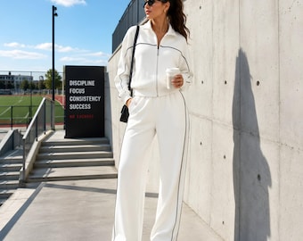 Conjunto deportivo blanco de estilo athleisure, chaqueta con cremallera, pantalones de pierna ancha y conjunto de descanso con ribetes en contraste.