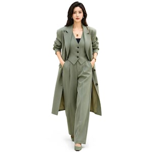 Pu&ograve; includere: Un completo a tre pezzi verde salvia composto da un cappotto lungo, un gilet e pantaloni a gamba larga. Il cappotto ha una chiusura con bottoni e spacchi laterali. Il gilet ha una chiusura con bottoni. I pantaloni hanno vita alta e tasche.