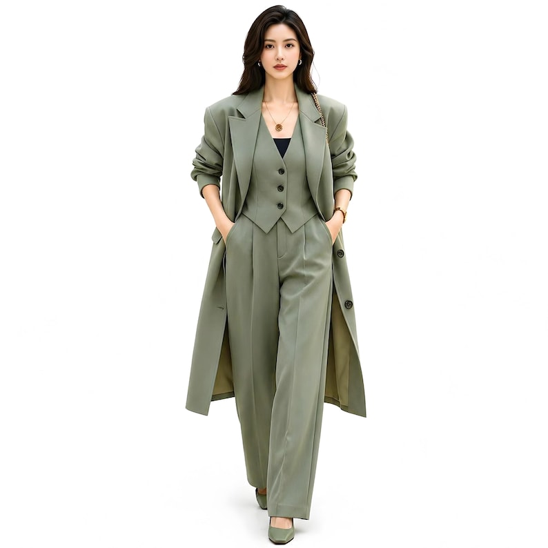 Pu&ograve; includere: Un completo a tre pezzi verde salvia composto da un cappotto lungo, un gilet e pantaloni a gamba larga. Il cappotto ha una chiusura con bottoni e spacchi laterali. Il gilet ha una chiusura con bottoni. I pantaloni hanno vita alta e tasche.