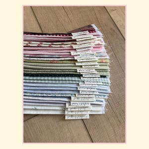 May include: A stack of folded fabric squares in various colors and patterns, including gingham, floral, and solid prints. Each piece of fabric features a small white fabric tag attached to the edge with the text Peony Projects printed on it.
