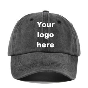 May include: A charcoal gray baseball cap with a curved brim. The cap features the text "Your logo here" in white block letters. The hat has a classic six-panel design and an adjustable strap.