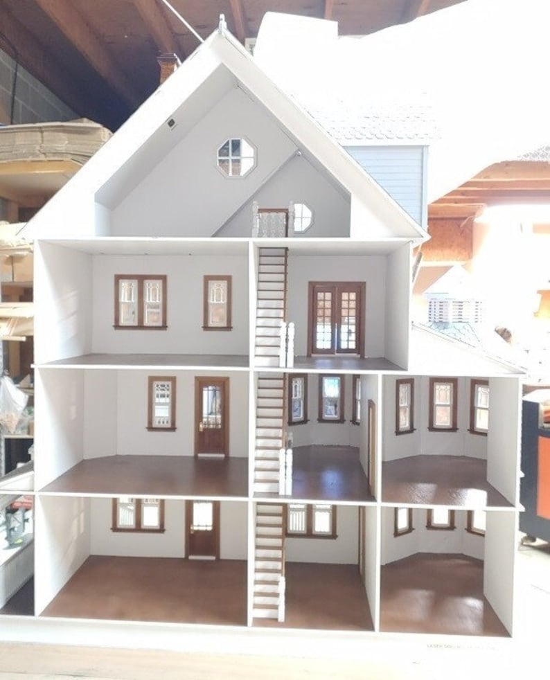 May include: A white dollhouse with four levels, a staircase, and windows. The dollhouse is open and the interior is visible. The floors are brown.