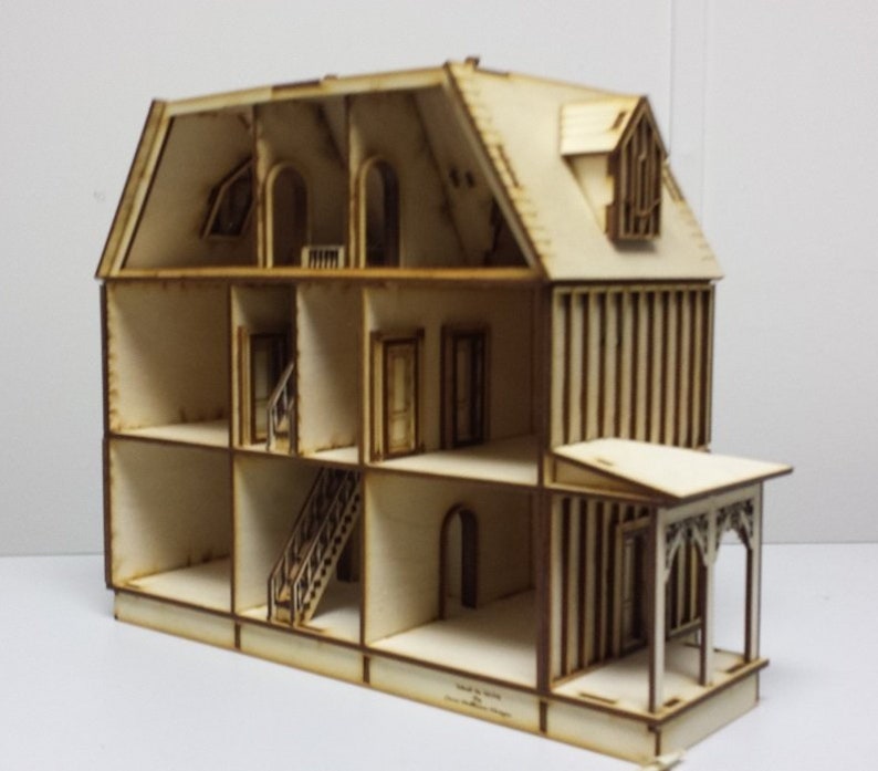 May include: A wooden dollhouse with a white paint finish. The dollhouse is open and shows the interior rooms and a staircase. The dollhouse has a porch with a decorative railing.