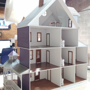 May include: A white dollhouse with a purple exterior and a white roof. The dollhouse is open and shows the interior rooms, which are painted white. The dollhouse has a porch with a white railing and a small gazebo.