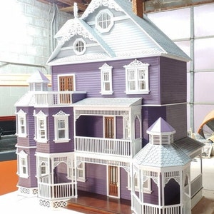 May include: A detailed dollhouse model with a purple exterior, white trim, and a wraparound porch. The dollhouse has a gabled roof, multiple windows, and a decorative cupola.