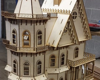 Puede incluir: Un modelo de madera de una casa de estilo victoriano con una torre, múltiples ventanas y detalles intrincados. El modelo está hecho de madera de color claro y está sin terminar.