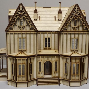 May include: A wooden model of a two-story house with a gabled roof, intricate details, and multiple windows. The house is painted in a light wood color and has a brown trim.