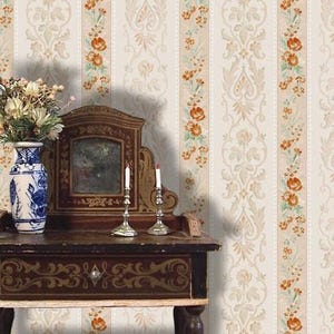 Puede incluir: Una escena de estilo vintage con una mesa de madera, un espejo y candelabros. Un jarr&oacute;n azul y blanco con flores est&aacute; sobre la mesa. El fondo es un papel pintado crema con motivos florales y damasco.