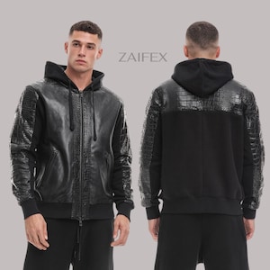 Op de afbeelding: Zwarte hoodie met imitatie krokodillenleer accenten op de schouders, mouwen en voorkant. De jas heeft een volledige ritssluiting en geribde manchetten en zoom. De merknaam ZAIFFEX staat rechtsboven gedrukt.
