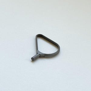 May include: A gray metal tool with a loop handle and a cylindrical end. The tool is designed with a triangular loop and a short, rounded extension. The object is set against a plain white background.