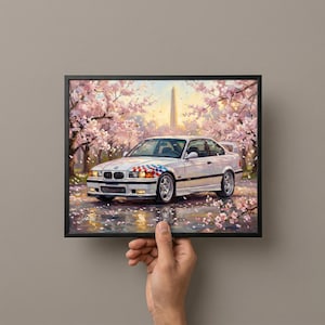 May include: A framed print of a white sports car with a checkered flag design on the front, parked on a wet road with cherry blossom trees in the background. The Washington Monument is visible in the distance.