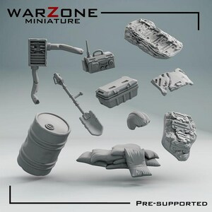May include: A collection of grey resin miniature gaming terrain pieces including a barrel, a shovel, a radio, a storage crate, a helmet, sandbags, and two textured debris slabs. The text WARZONE MINIATURE and PRE-SUPPORTED is visible.