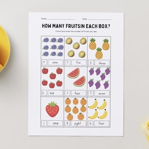 Könnte beinhalten: Ein Arbeitsblatt mit dem Titel "HOW MANY FRUITS IN EACH BOX?" zeigt Illustrationen von Früchten wie Blaubeeren, Kiwis, Ananas, Äpfeln, Wassermelonen, Trauben, einer Erdbeere, Orangen und Bananen. Jede Fruchtgruppe wird von einer Zahl und einem Wort begleitet.