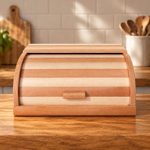 May include: A rectangular bread box featuring a roll-top door constructed from alternating horizontal slats of light and medium-toned wood. The unit includes a small, centered wooden handle on the front panel and a solid base frame.